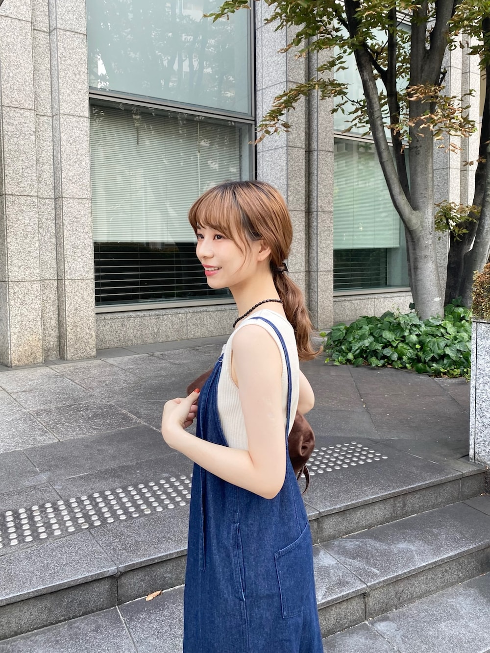 ブルー系のワンピース、ブラウン系のトートバッグ、ホワイト系のタンクトップを着用したレディースの秋コーディネートの6枚目の写真