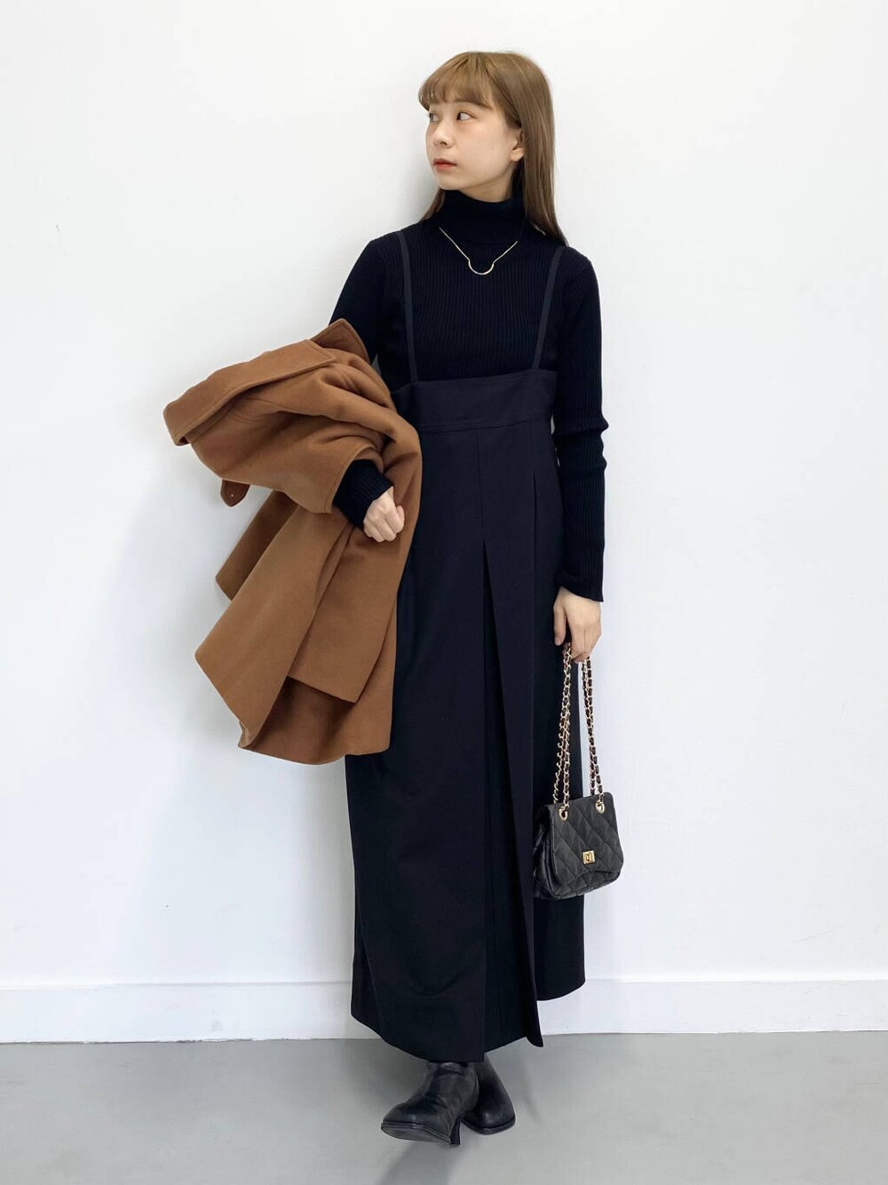 ブラック系のショルダーバッグ、ブラック系のブーツ、ブラック系のワンピースを着用したレディースの冬コーディネートの4枚目の写真