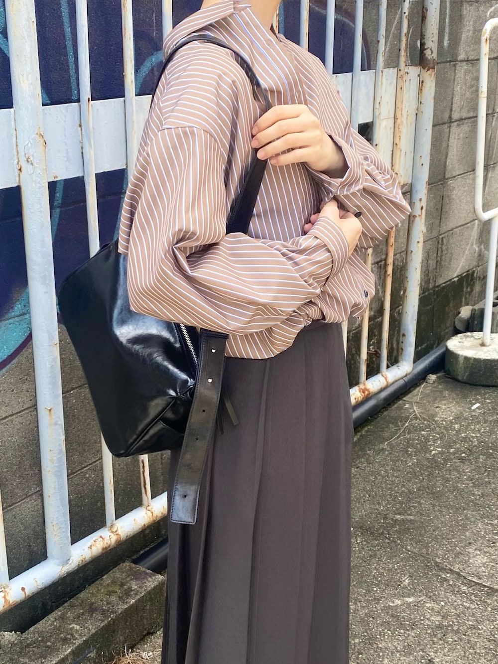 グレー系のスカート、ブラウン系のシャツ/ブラウス、ブラック系のローファーを着用したレディースの秋コーディネートの3枚目の写真