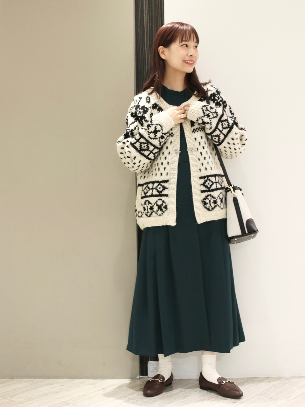 ホワイト系のカーディガン/ボレロ、グリーン系のワンピース、ブラック系のショルダーバッグを着用したレディースの冬コーディネートの2枚目の写真