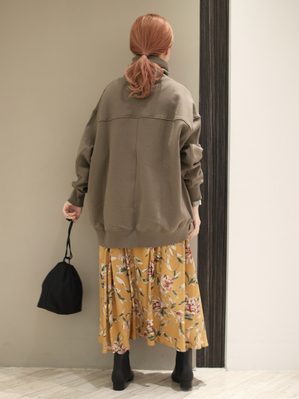 グリーン系のスウェット、オレンジ系のスカート、ブラック系のショルダーバッグを着用したレディースの秋コーディネートの5枚目の写真