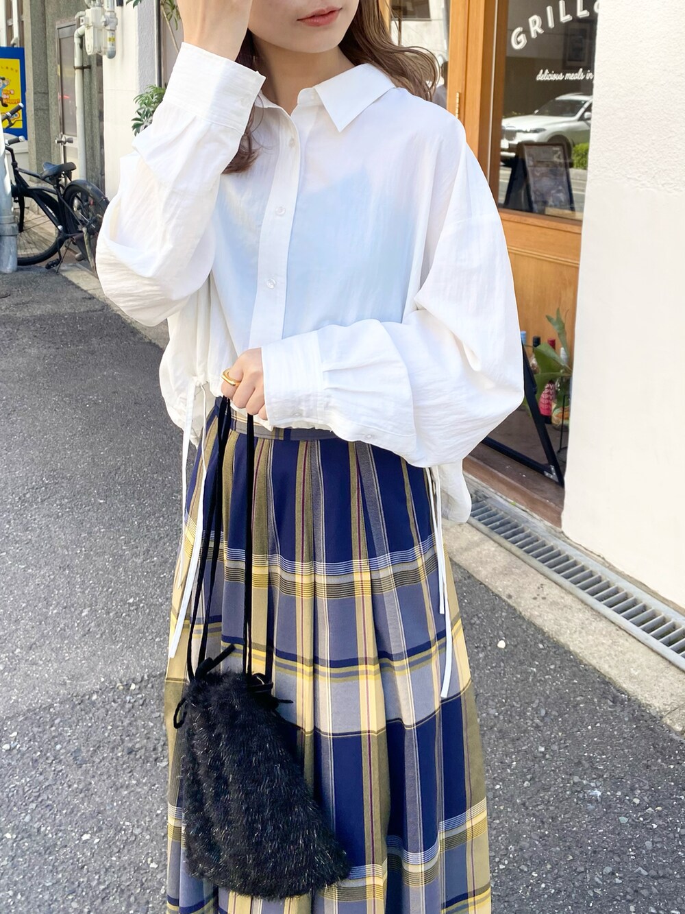 ブルー系のスカート、ホワイト系のシャツ/ブラウス、ブラック系のショルダーバッグを着用したレディースの秋コーディネートの3枚目の写真