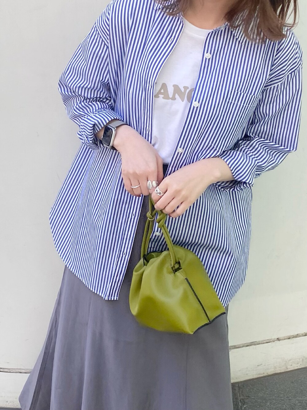 グリーン系のショルダーバッグ、グレー系のスカート、ブルー系のシャツ/ブラウスを着用したレディースの春コーディネートの2枚目の写真