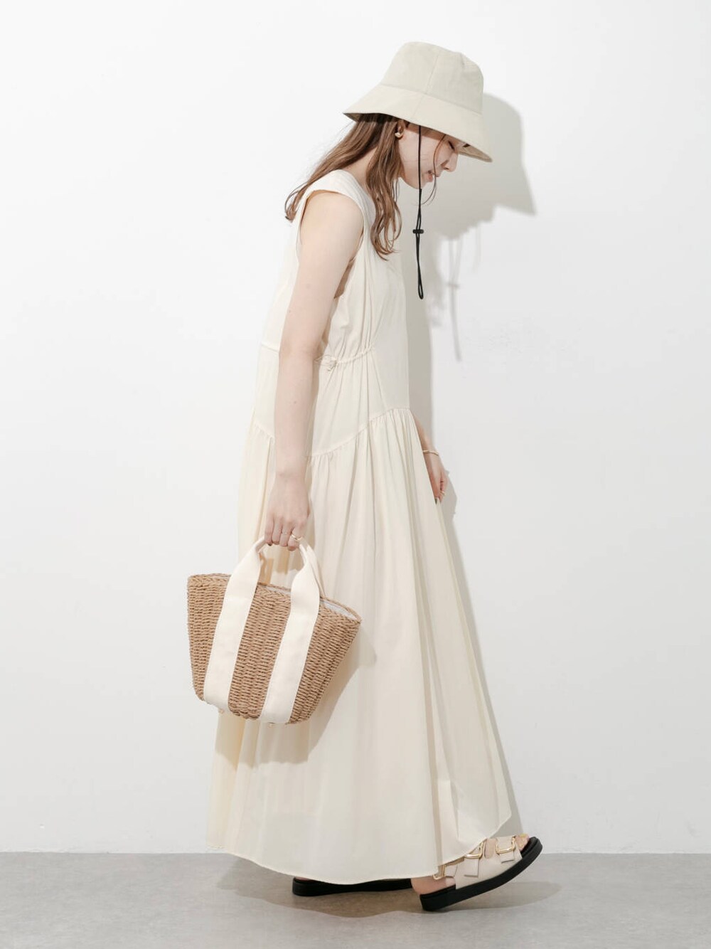 ベージュ系のハンドバッグ、グレー系のサンダル、ホワイト系のワンピースを着用したレディースの夏コーディネートの2枚目の写真