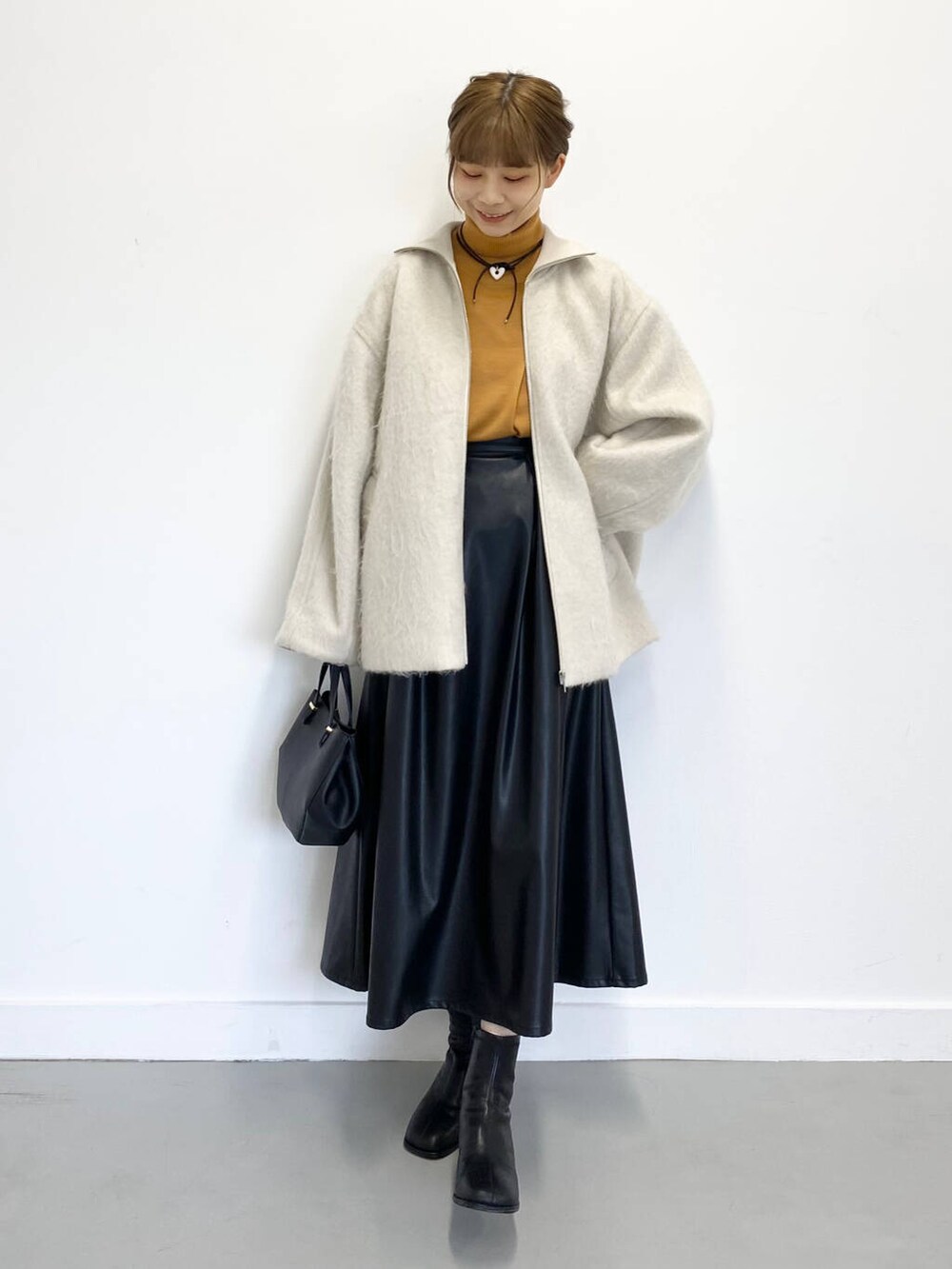 イエロー系のニット/セーター、ブラック系のショルダーバッグ、ブラック系のブーツを着用したレディースの冬コーディネートの5枚目の写真