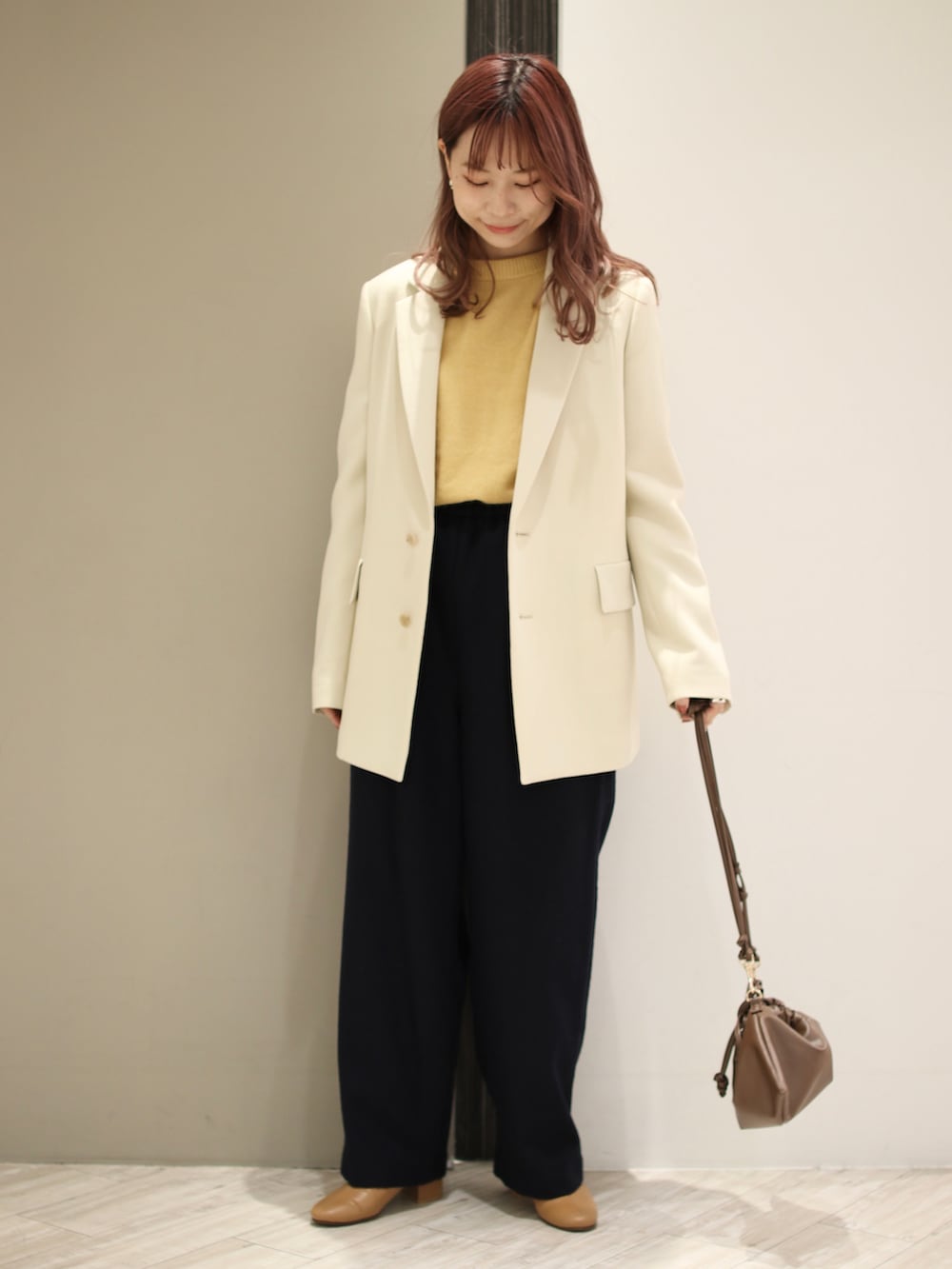 イエロー系のニット/セーター、ブラウン系のハンドバッグ、イエロー系のブーツを着用したレディースの冬コーディネートの5枚目の写真