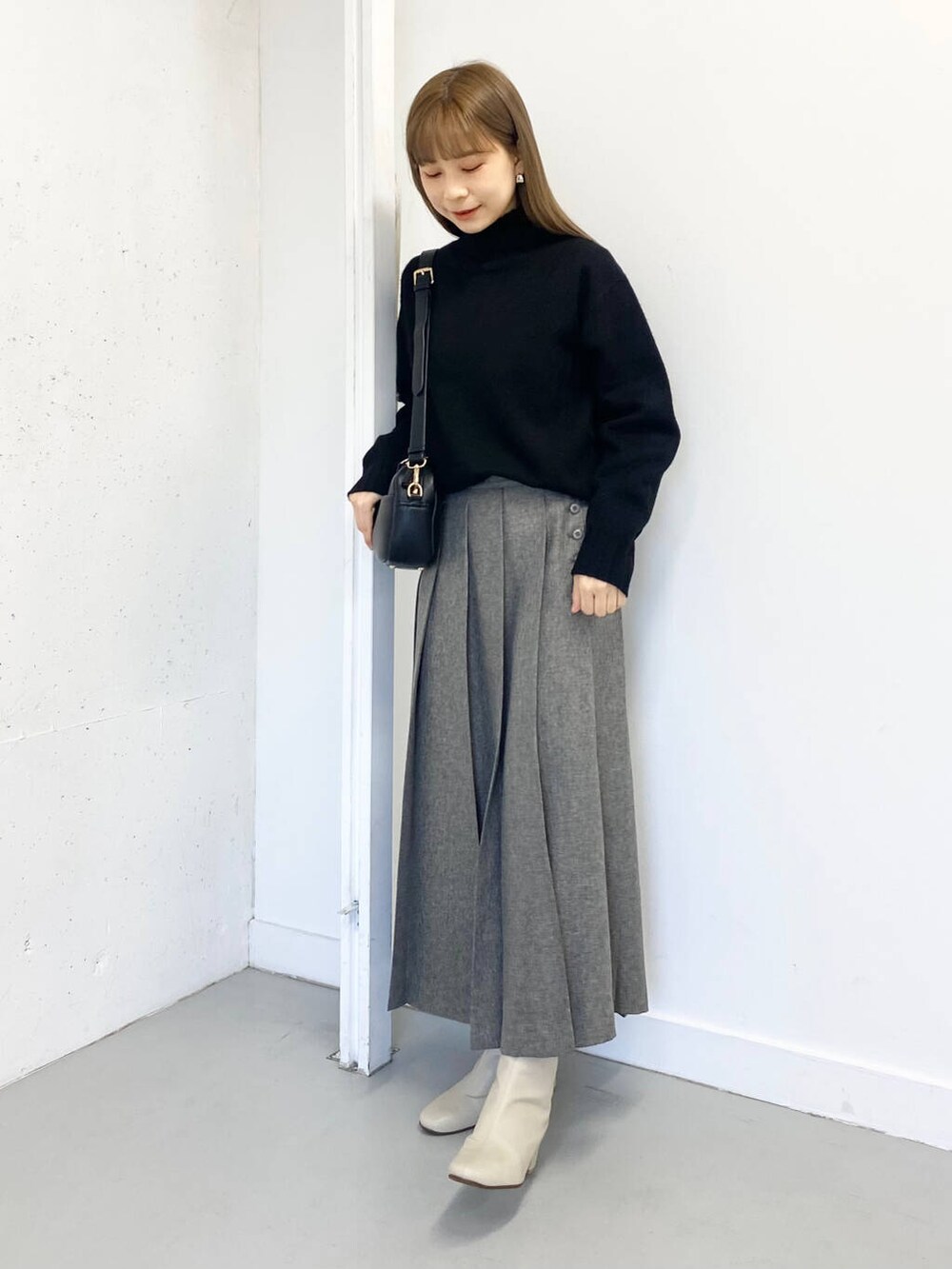 ホワイト系のブーツ、ブラック系のショルダーバッグ、グレー系のスカートを着用したレディースの冬コーディネートの4枚目の写真