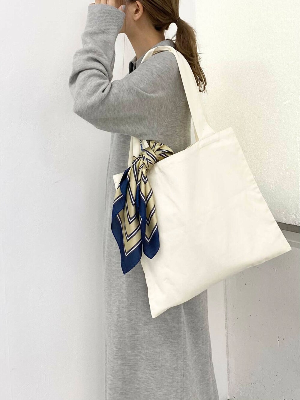 ブラック系のブーツ、ホワイト系のトートバッグ、グレー系のワンピースを着用したレディースの秋コーディネートの7枚目の写真