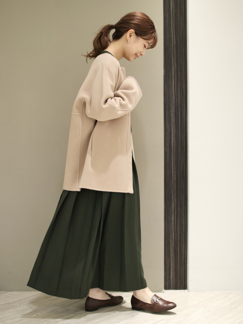 ブラウン系のトートバッグ、ブラウン系のローファー、グリーン系のワンピースを着用したレディースの秋コーディネートの3枚目の写真