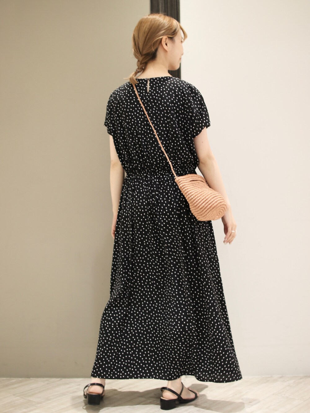 ブラック系のワンピース、ベージュ系のかごバッグ、ブラック系のサンダルを着用したレディースの夏コーディネートの2枚目の写真