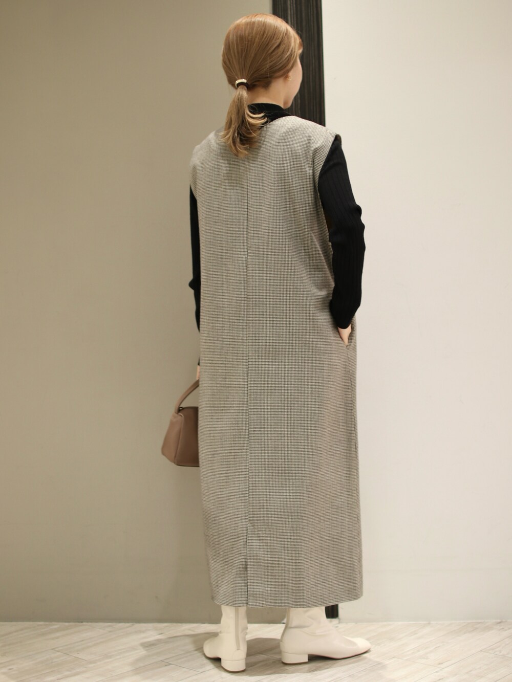 ブラウン系のハンドバッグ、ホワイト系のブーツ、ベージュ系のワンピースを着用したレディースの冬コーディネートの4枚目の写真