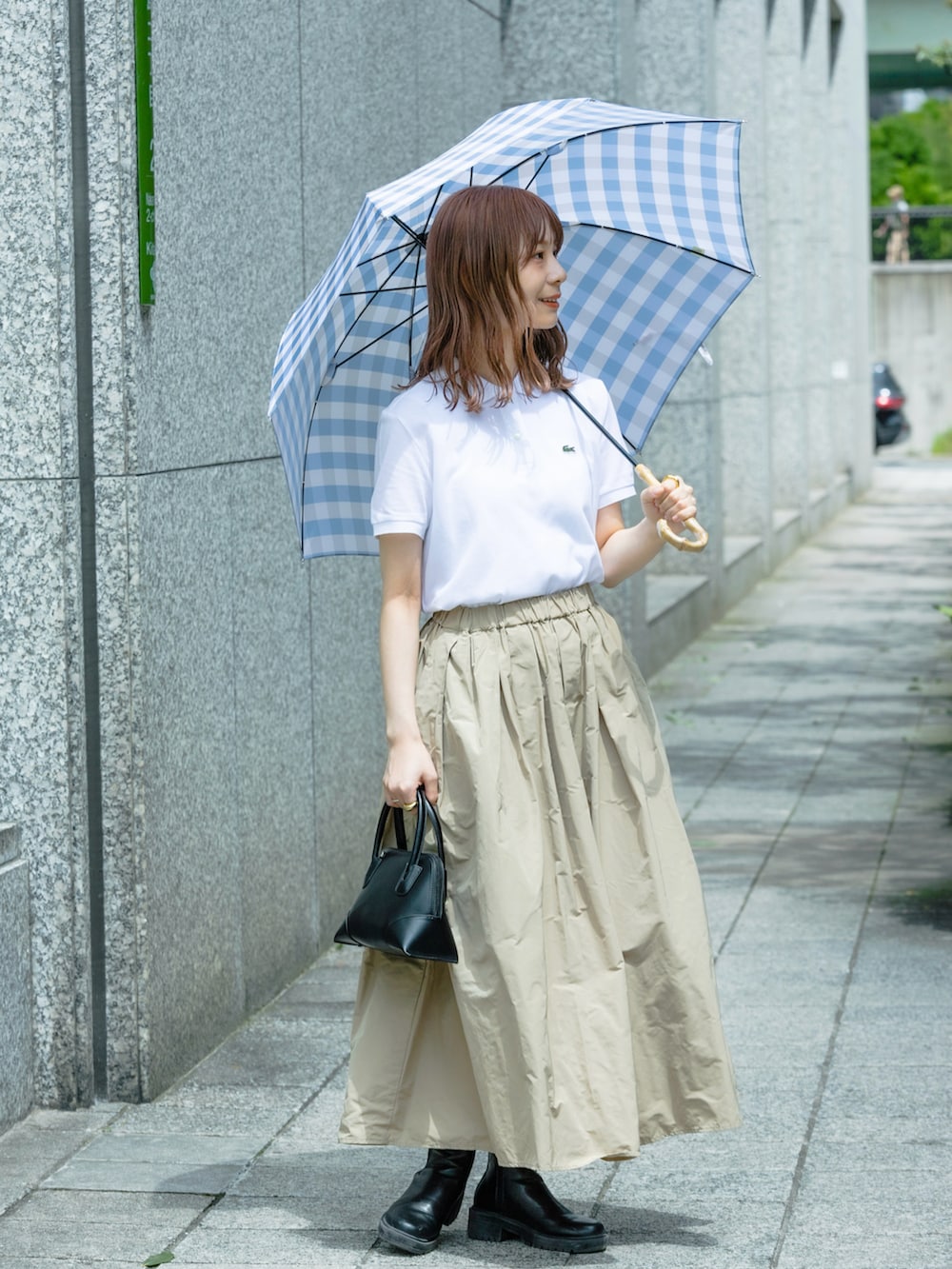 ホワイト系のポロシャツ、ブラック系のショルダーバッグ、ベージュ系のスカートを着用したレディースの春コーディネートの2枚目の写真