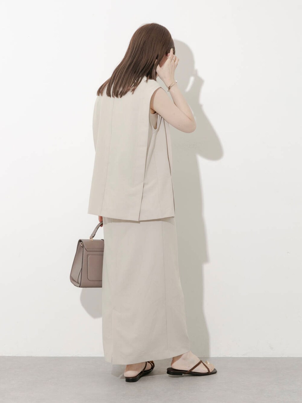 グレー系のハンドバッグ、ブラウン系のサンダル、ベージュ系のワンピースを着用したレディースの夏コーディネートの6枚目の写真