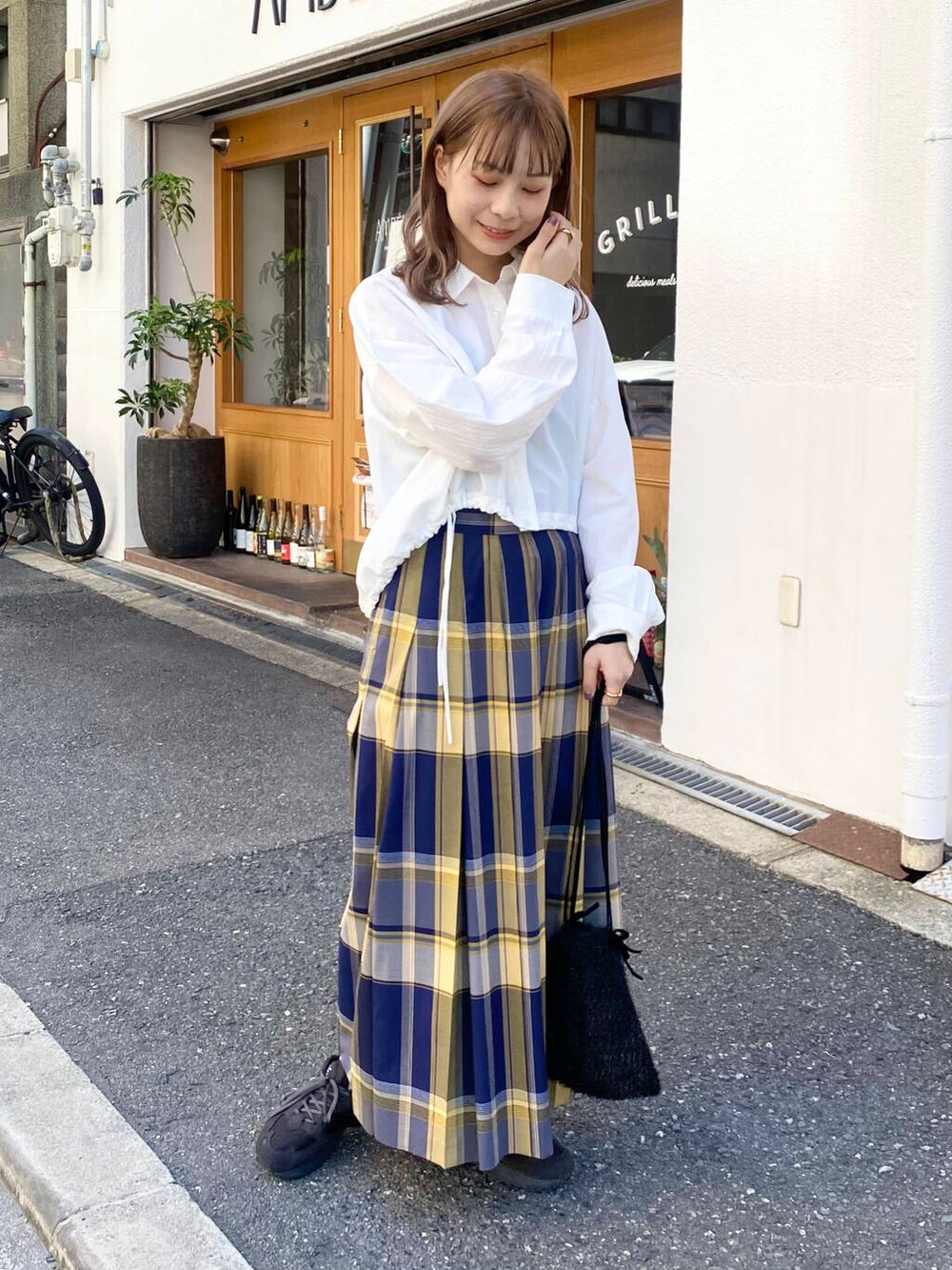 グレー系のスニーカー、ホワイト系のシャツ/ブラウス、ブルー系のスカートを着用したレディースの秋コーディネートの2枚目の写真