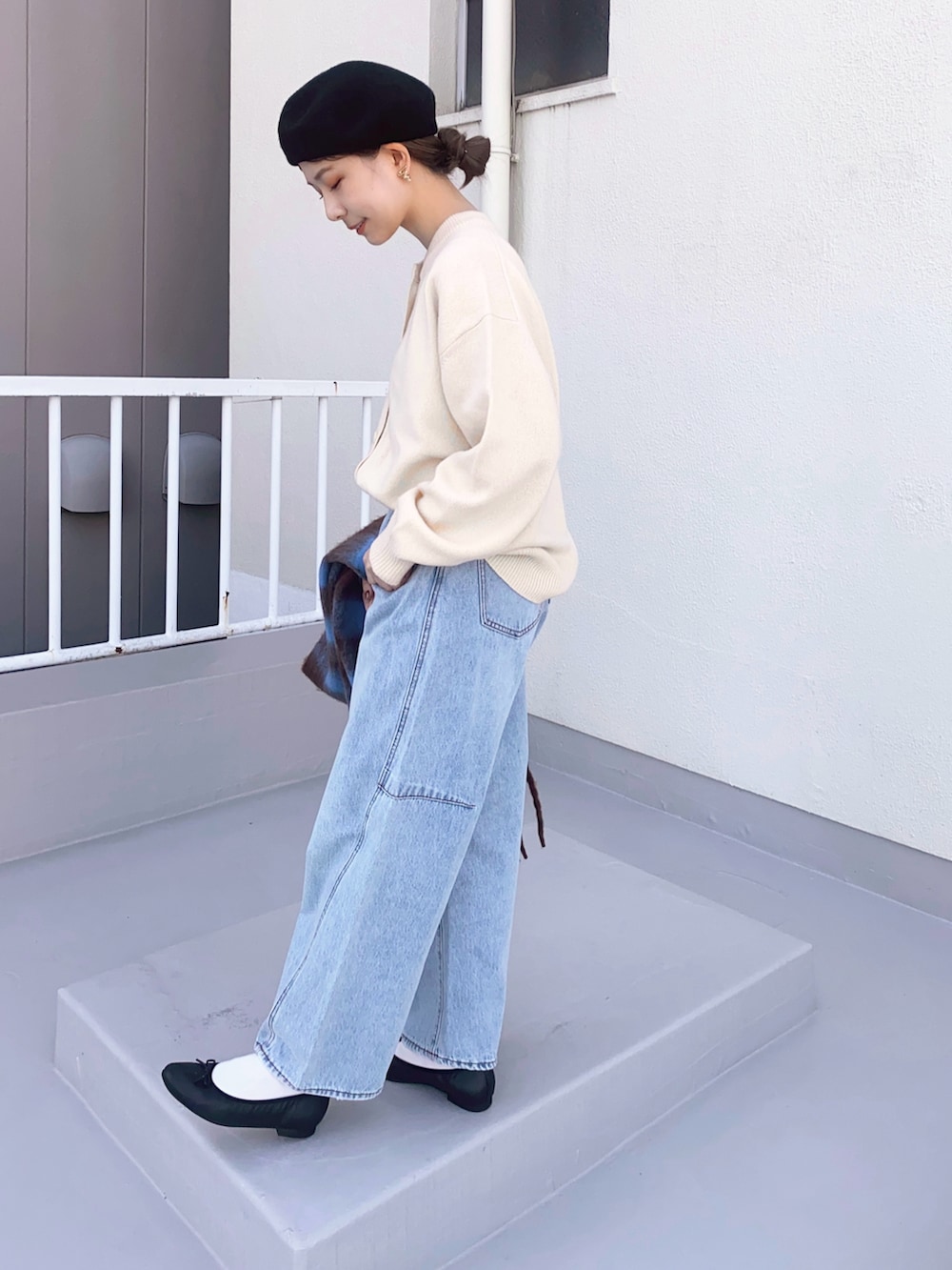 ブルー系のデニムパンツ、ブラック系のバレエシューズ、ホワイト系のカーディガン/ボレロを着用したレディースの冬コーディネートの2枚目の写真