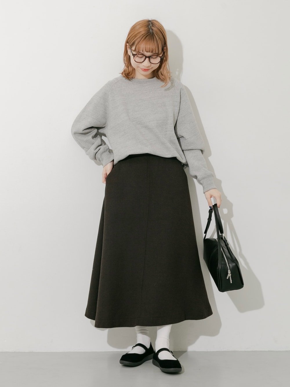 グレー系のスカート、ブラック系のその他シューズ、グレー系のスウェットを着用したレディースの秋コーディネートの2枚目の写真