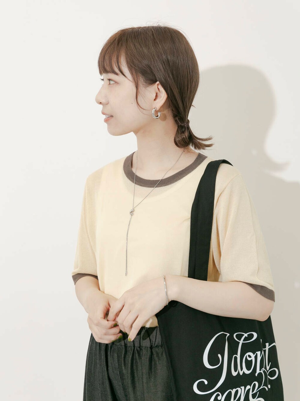 ブラック系のトートバッグ、ベージュ系のニット/セーター、ホワイト系のサンダルを着用したレディースの夏コーディネートの2枚目の写真