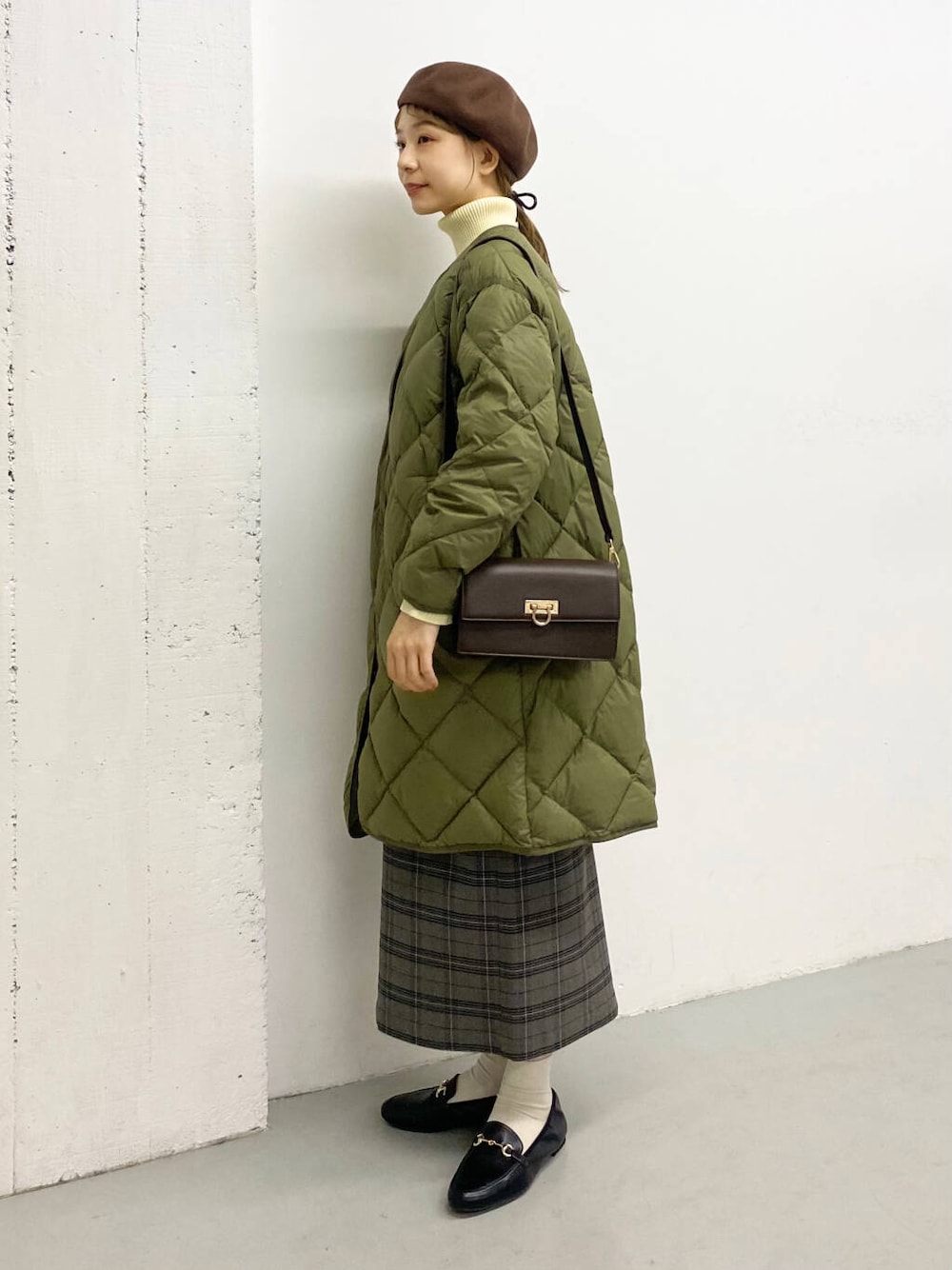 ブラック系のローファー、グリーン系のダウンジャケット/コート、ブラウン系のショルダーバッグを着用したレディースの冬コーディネートの2枚目の写真