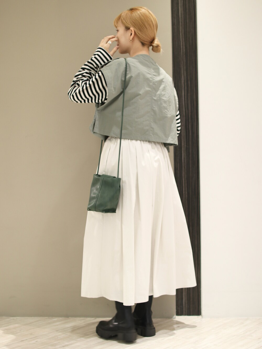 ホワイト系のスカート、グリーン系のベスト、ブラック系のTシャツ/カットソーを着用したレディースの秋コーディネートの3枚目の写真