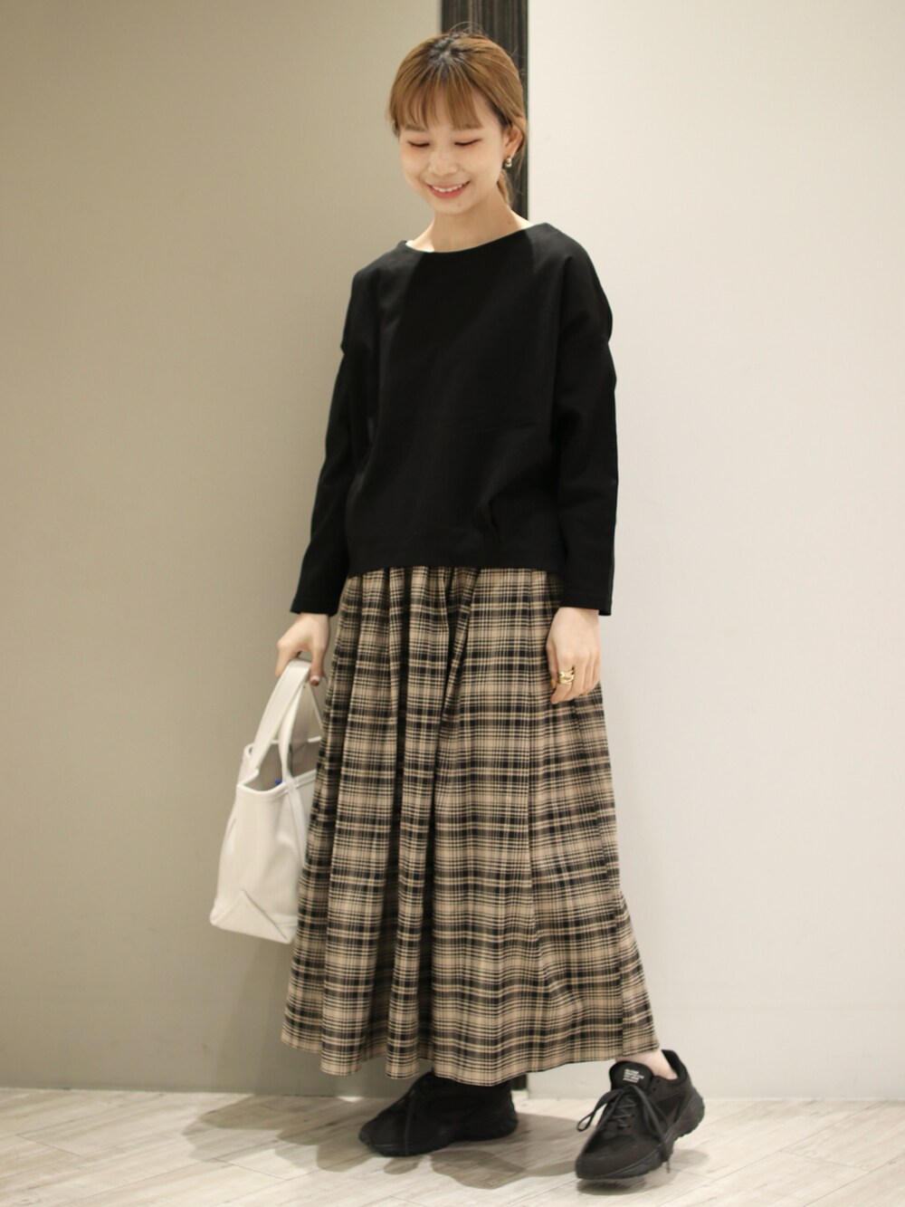 ベージュ系のトートバッグ、ベージュ系のスカート、ブラック系のTシャツ/カットソーを着用したレディースの冬コーディネートの2枚目の写真