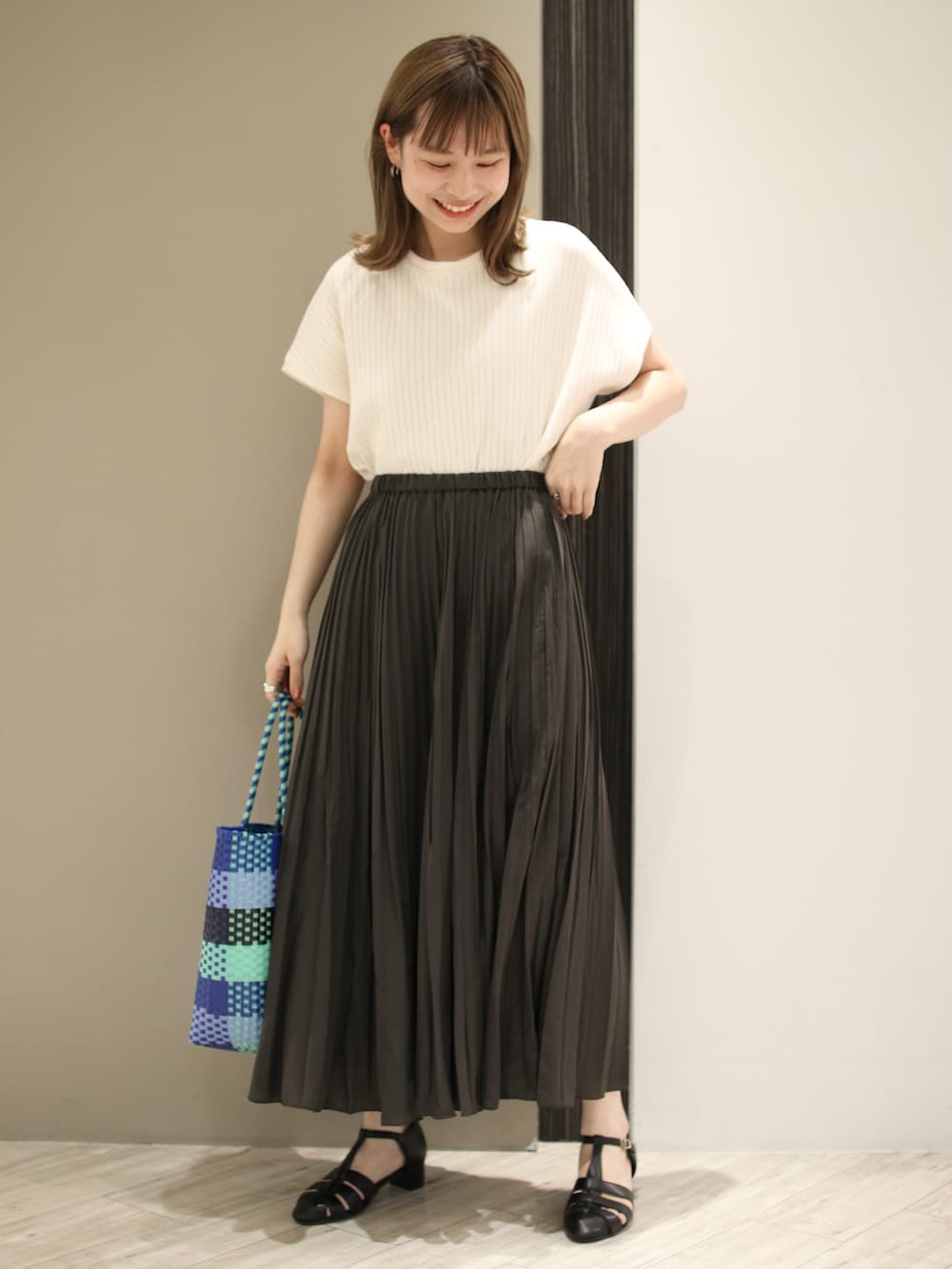 ブルー系のトートバッグ、ブラック系のサンダル、グレー系のスカートを着用したレディースの夏コーディネートの2枚目の写真