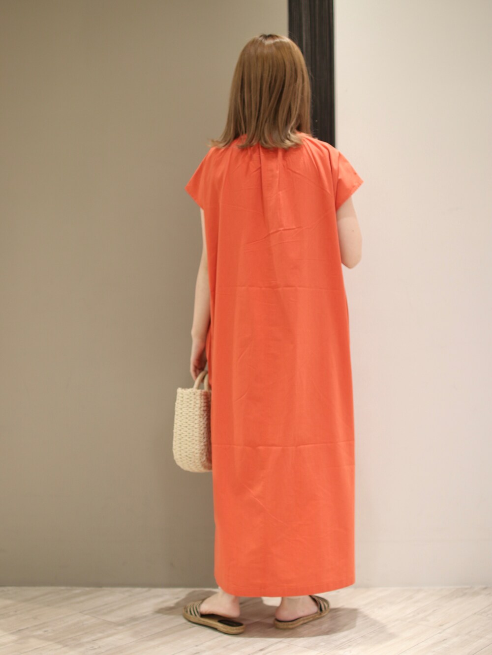 オレンジ系のワンピース、ホワイト系のハンドバッグ、ベージュ系のサンダルを着用したレディースの夏コーディネートの3枚目の写真