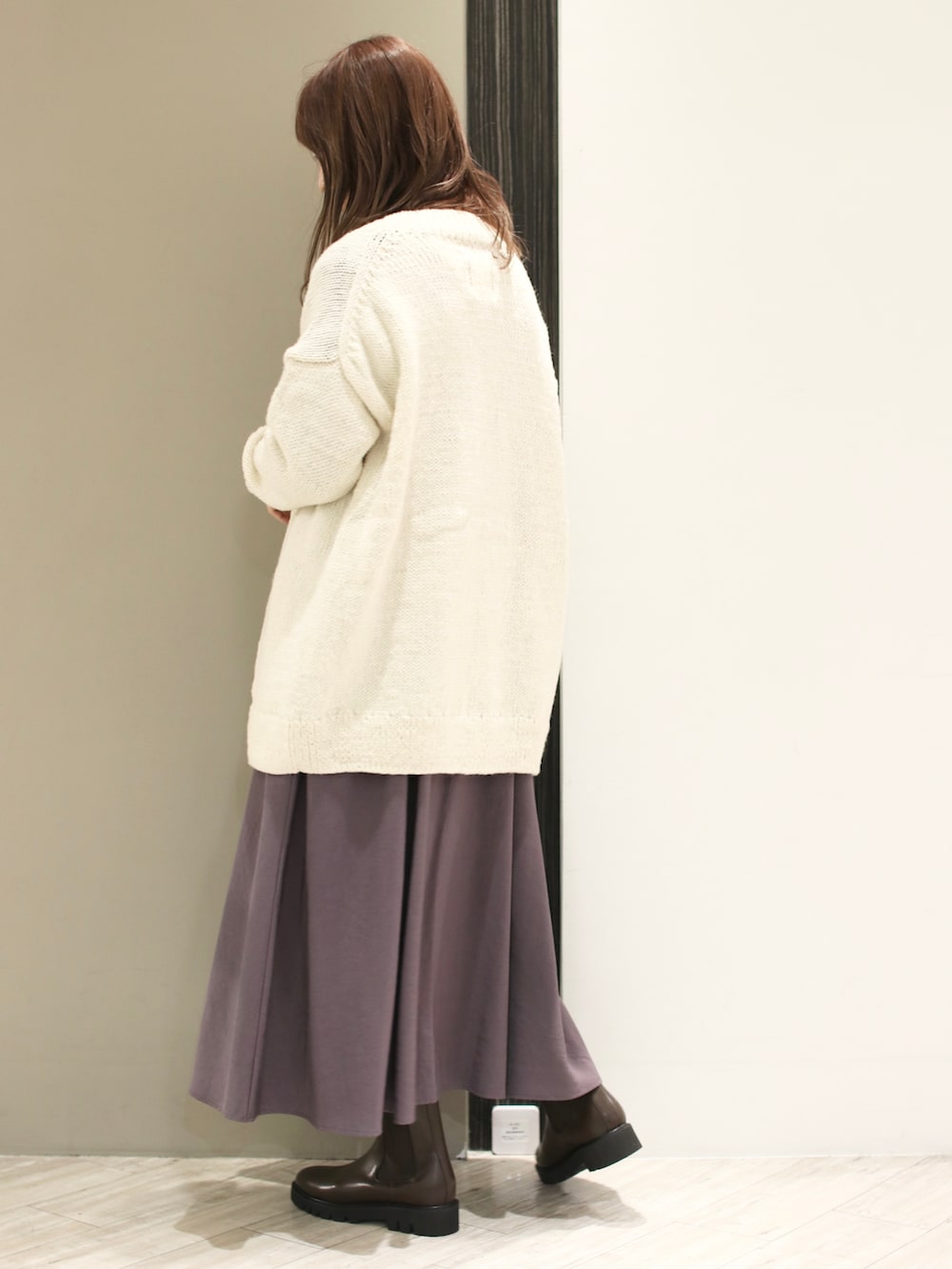 グレー系のワンピース、ホワイト系のカーディガン/ボレロ、ブラック系のショルダーバッグを着用したレディースの冬コーディネートの3枚目の写真