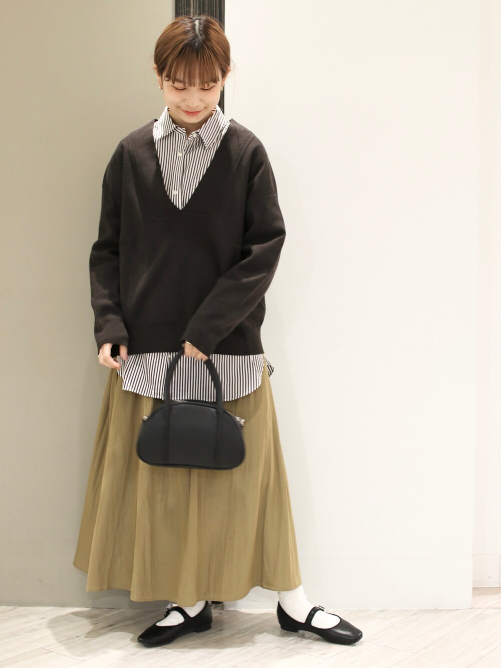 グレー系のニット/セーター、ブラウン系のシャツ/ブラウス、イエロー系のスカートを着用したレディースの冬コーディネートの2枚目の写真