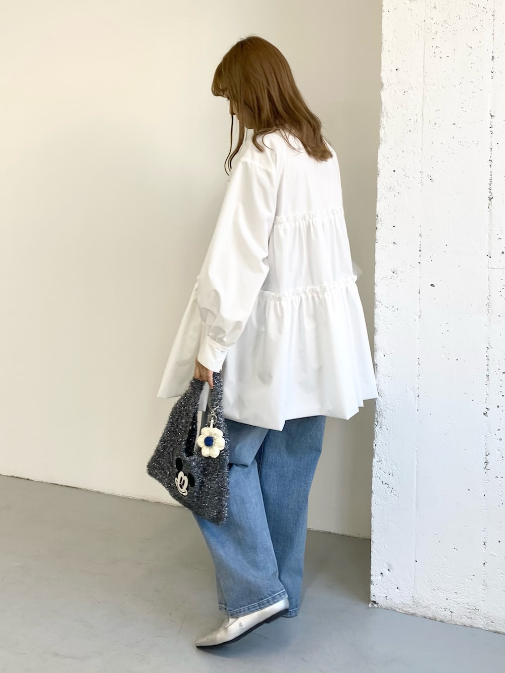 ホワイト系のワンピース、ブルー系のデニムパンツ、ブラック系のトートバッグを着用したレディースの冬コーディネートの4枚目の写真