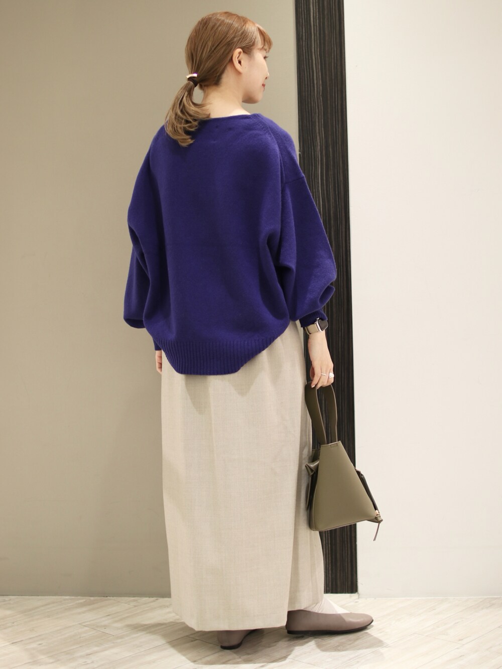 ベージュ系のスカート、グリーン系のショルダーバッグ、ブルー系のニット/セーターを着用したレディースの秋コーディネートの3枚目の写真