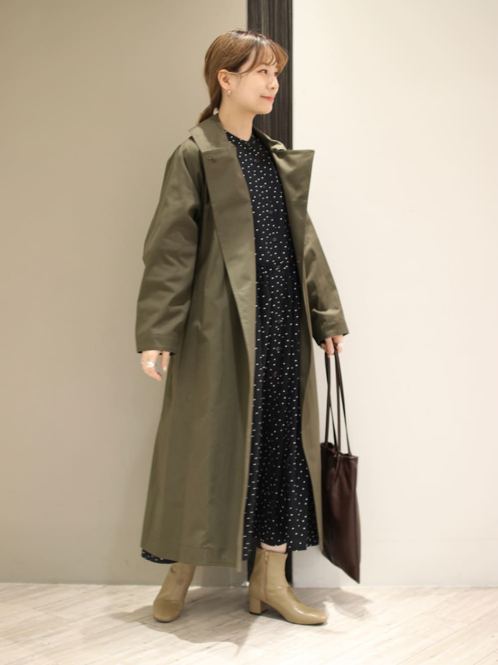 ブラウン系のトートバッグ、ベージュ系のブーツ、ブラック系のワンピースを着用したレディースの冬コーディネートの3枚目の写真