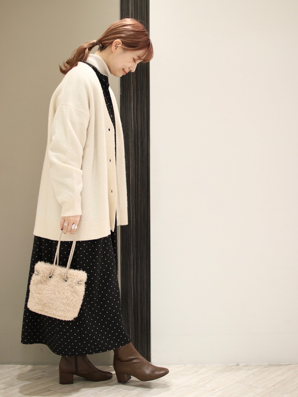 ベージュ系のハンドバッグ、ブラウン系のブーツ、ブラック系のワンピースを着用したレディースの冬コーディネートの4枚目の写真