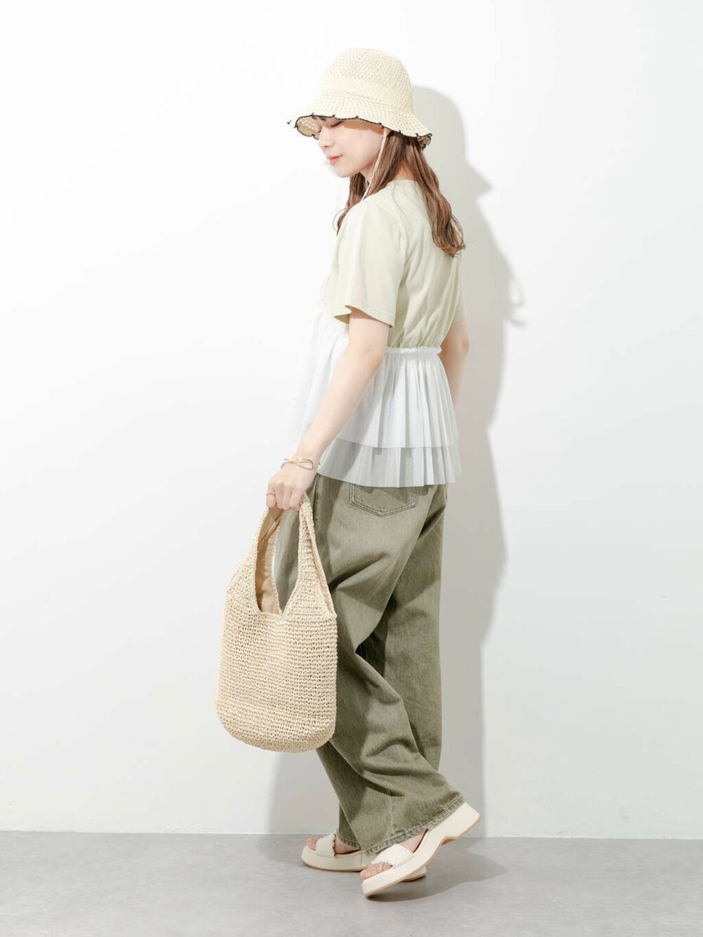 ベージュ系のトートバッグ、グリーン系のTシャツ/カットソー、ホワイト系のサンダルを着用したレディースの夏コーディネートの4枚目の写真