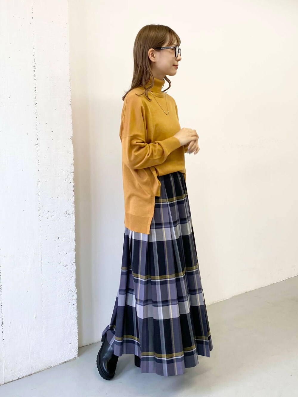 イエロー系のニット/セーター、ブラック系のブーツ、ブラック系のスカートを着用したレディースの秋コーディネートの2枚目の写真