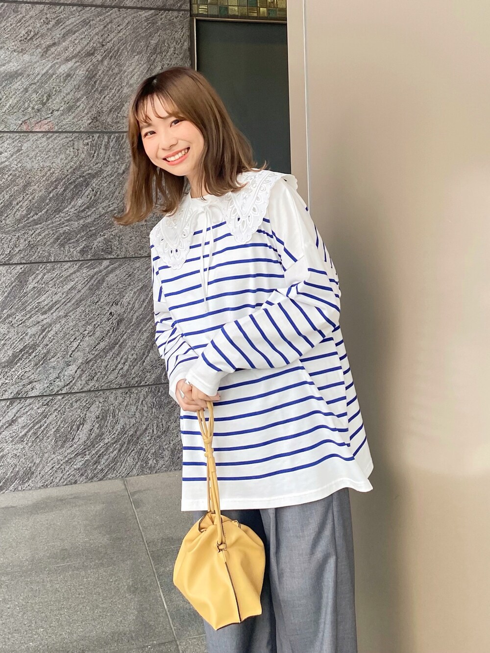 ベージュ系のショルダーバッグ、イエロー系のスニーカー、グレー系のその他パンツを着用したレディースの春コーディネートの2枚目の写真