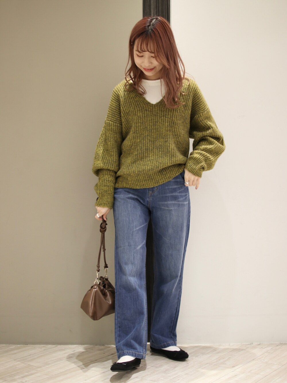 ブルー系のデニムパンツ、ブラウン系のハンドバッグ、ブラック系のバレエシューズを着用したレディースの冬コーディネートの2枚目の写真