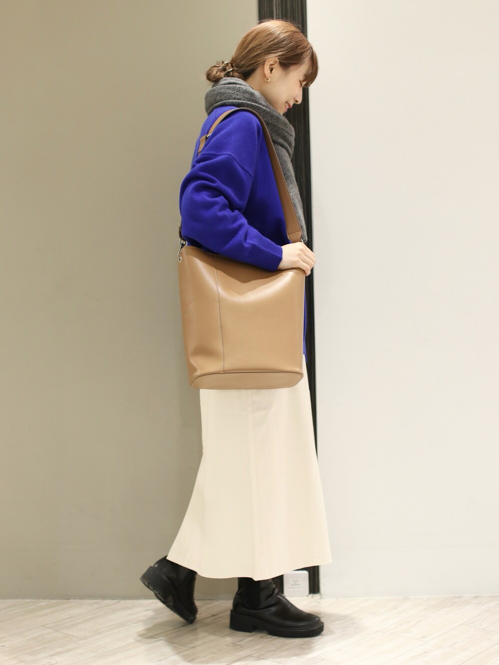 ブラウン系のショルダーバッグ、ホワイト系のスカート、ブラック系のブーツを着用したレディースの冬コーディネートの3枚目の写真