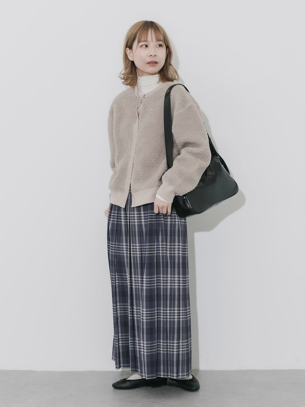 グレー系のスカート、ベージュ系のカーディガン/ボレロ、ブラック系のショルダーバッグを着用したレディースの秋コーディネートの4枚目の写真