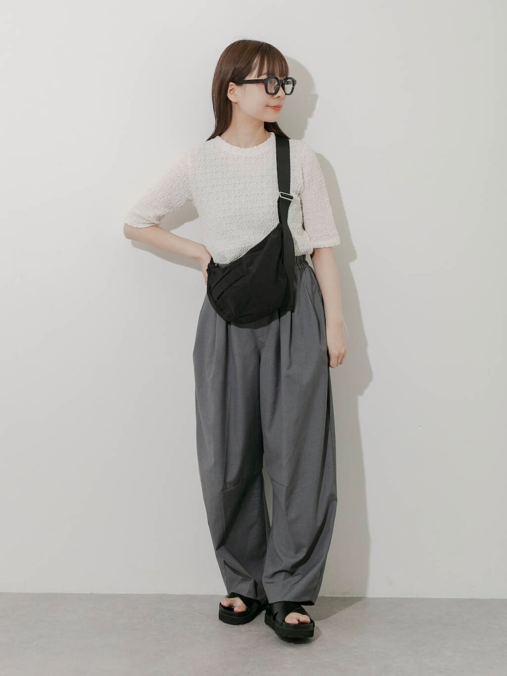 グレー系のその他パンツ、ホワイト系のTシャツ/カットソー、ブラック系のサンダルを着用したレディースの春コーディネートの3枚目の写真
