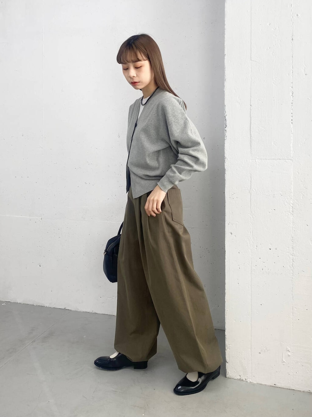 ブラック系のボストンバッグ、ブラック系のローファー、グレー系のカーディガン/ボレロを着用したレディースの春コーディネートの2枚目の写真