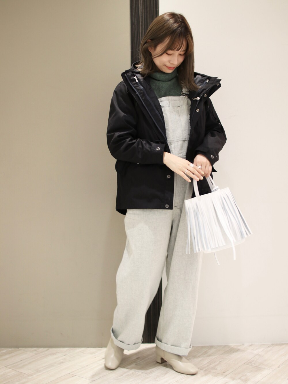 ブルー系のサロペット/オーバーオール、グリーン系のニット/セーター、ブルー系のマウンテンパーカーを着用したレディースの冬コーディネートの2枚目の写真