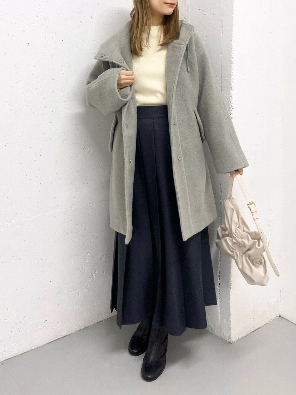 グリーン系のその他アウター、ホワイト系のニット/セーター、ブラック系のブーツを着用したレディースの冬コーディネートの3枚目の写真