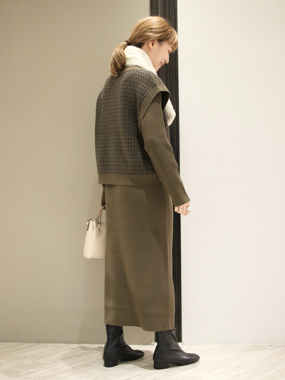 ホワイト系のトートバッグ、グリーン系のワンピース、ブラック系のブーツを着用したレディースの秋コーディネートの4枚目の写真