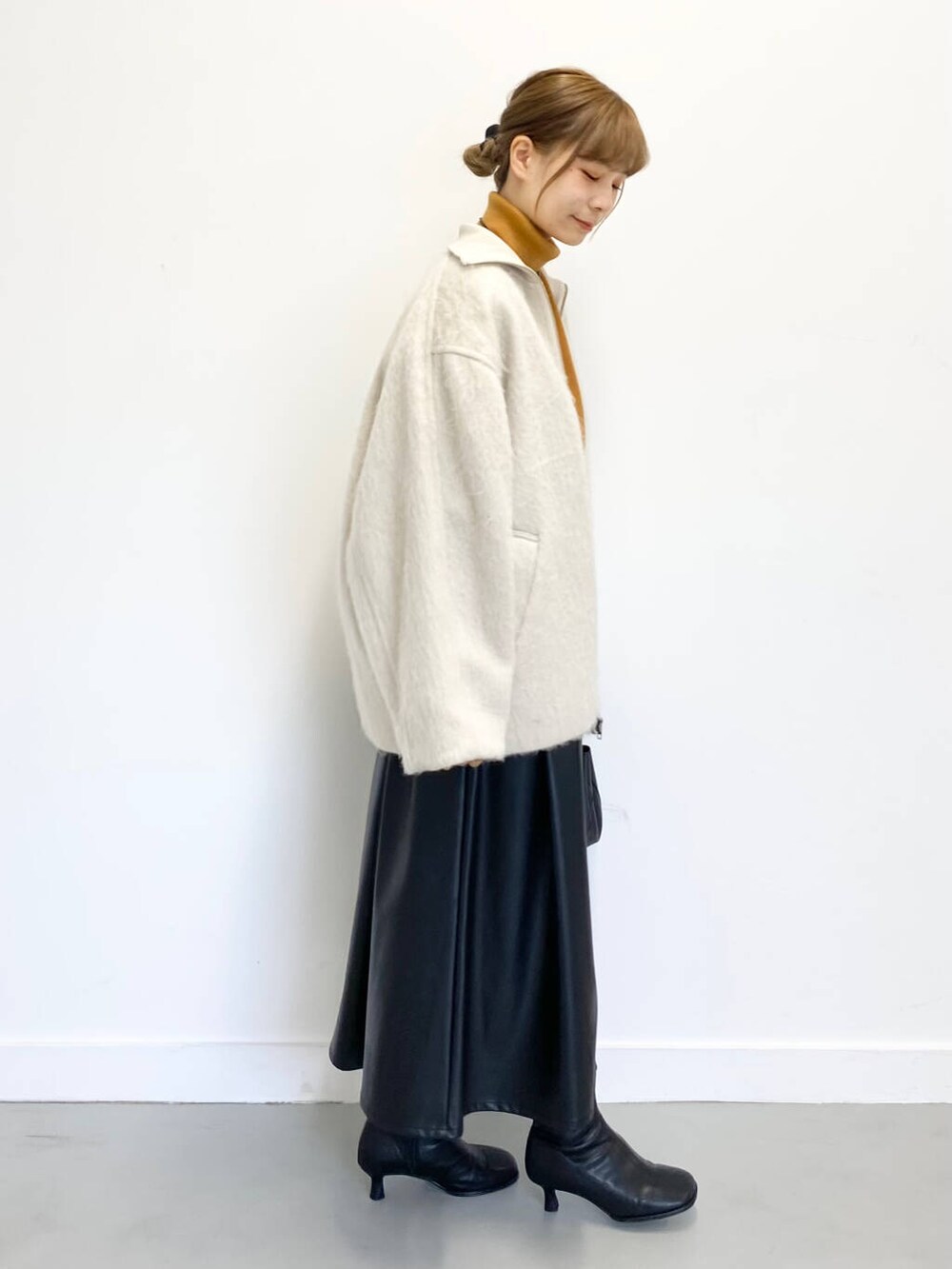 イエロー系のニット/セーター、ブラック系のショルダーバッグ、ブラック系のブーツを着用したレディースの冬コーディネートの3枚目の写真