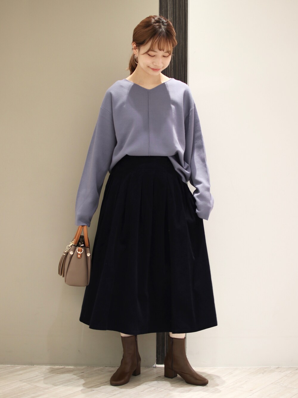 ベージュ系のトートバッグ、ブルー系のスカート、ブルー系のニット/セーターを着用したレディースの秋コーディネートの2枚目の写真
