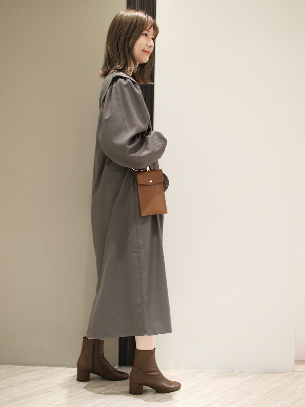 グレー系のワンピース、ブラウン系のブーツ、ブラウン系のショルダーバッグを着用したレディースの冬コーディネートの2枚目の写真