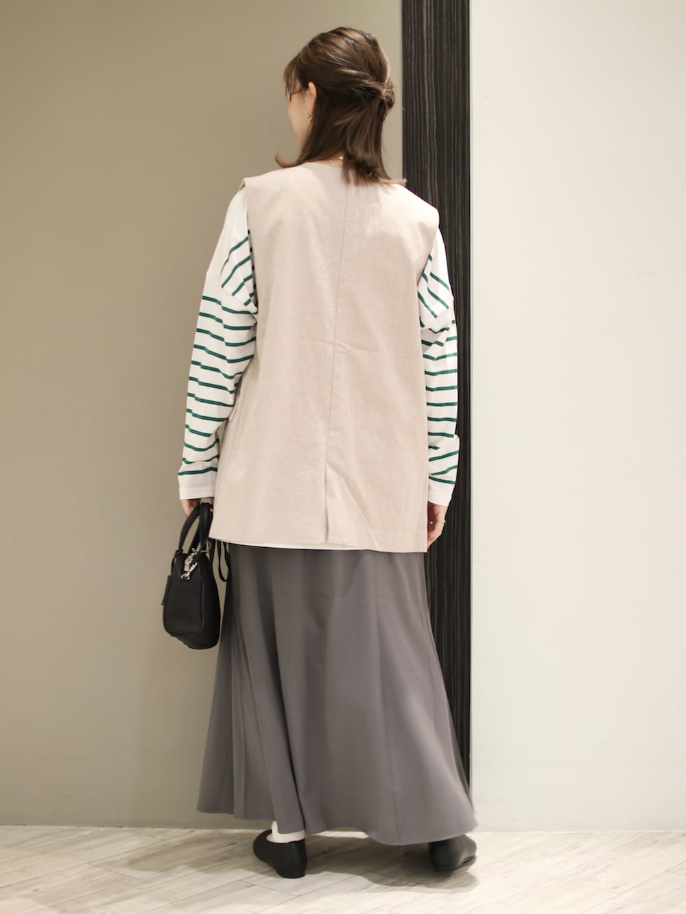 ブラック系のボストンバッグ、グリーン系のTシャツ/カットソー、グレー系のスカートを着用したレディースの春コーディネートの4枚目の写真