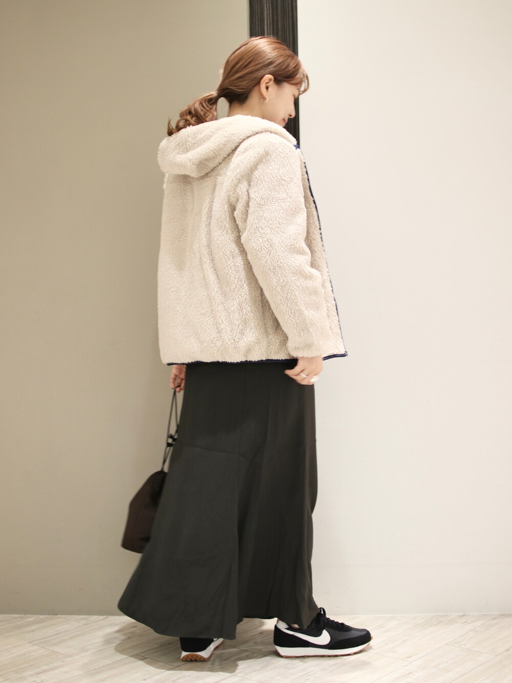 ブラック系のスニーカー、グレー系のスカート、ブラウン系のショルダーバッグを着用したレディースの秋コーディネートの4枚目の写真