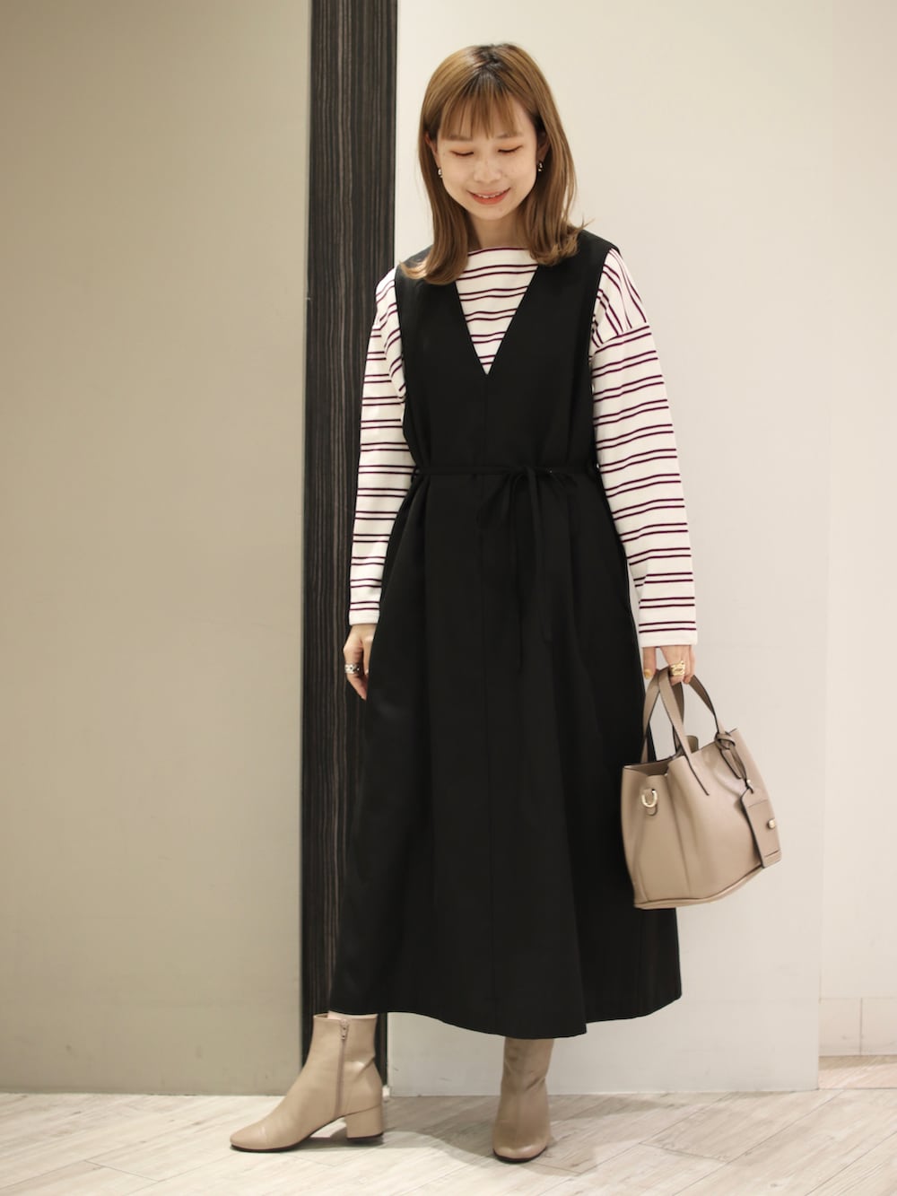 パープル系のTシャツ/カットソー、ブラック系のワンピース、ベージュ系のトートバッグを着用したレディースの秋コーディネートの4枚目の写真