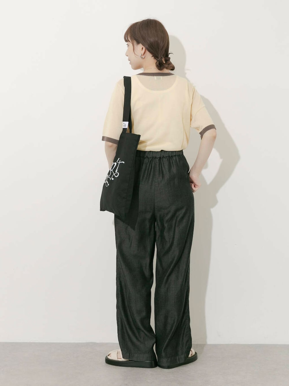 ブラック系のトートバッグ、ベージュ系のニット/セーター、ホワイト系のサンダルを着用したレディースの夏コーディネートの6枚目の写真